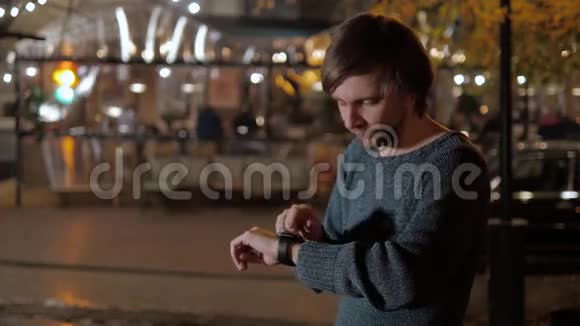夜间街上带智能手表的男性游客远望触摸手表视频的预览图