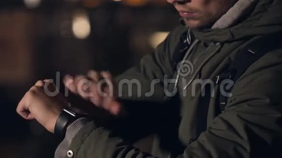 夜间街上带智能手表的男性游客远望触摸手表视频的预览图