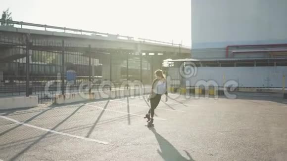 漂亮漂亮的年轻女子骑着轮滑在街上跳舞城市背景视频的预览图