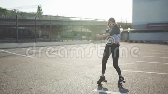 漂亮漂亮的年轻女子骑着轮滑在街上跳舞城市背景视频的预览图
