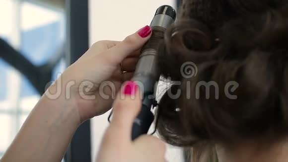 发型师用电动卷发器在顾客头发上做卷发视频的预览图