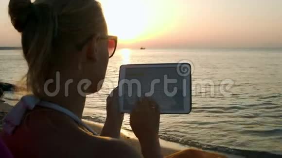 日落时分坐在海边的女人正在打电话视频的预览图