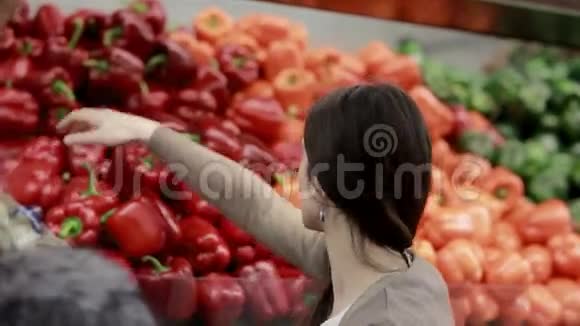 年轻女人在商店货架上选择辣椒视频的预览图