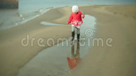 小美丽的女孩带着雨伞在雨中玩耍沿着海岸散步视频的预览图