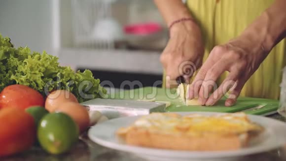 在厨房桌子上切软奶酪做三明治女人的手视频的预览图