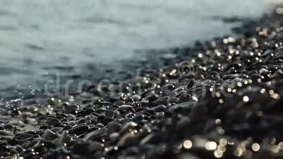 特写电影波浪和水滴再次拍打鹅卵石海滩的浅田深视频的预览图