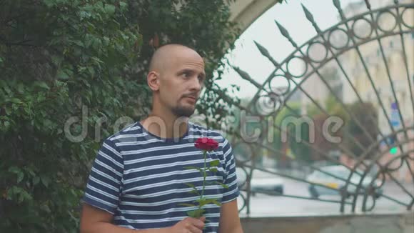 悲伤的年轻人带着玫瑰等待一个迟到的女人视频的预览图
