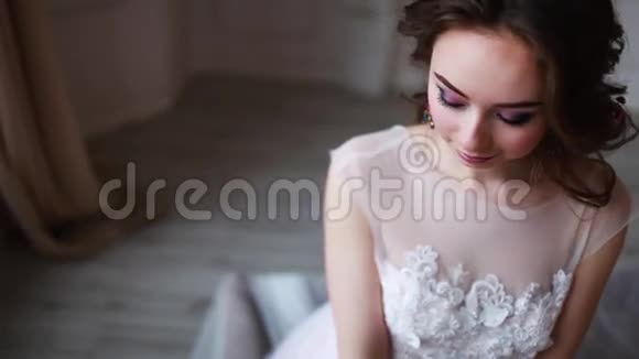 身着粉色婚纱的女孩正坐在一间漂亮的房间里周围是鲜花和蜡烛视频的预览图