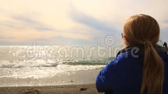 天气不好一个女人独自坐在荒无人烟的海滩上看着大海吃披萨视频的预览图