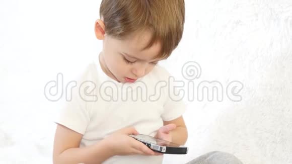 快乐的孩子在白色背景下玩智能手机特写镜头视频的预览图