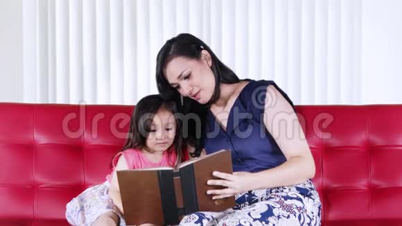 女孩和母亲在沙发上看书视频的预览图