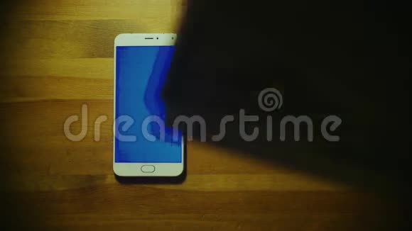 男性手把一大笔钱扔在白色智能手机上木制表面有蓝色钥匙视频的预览图