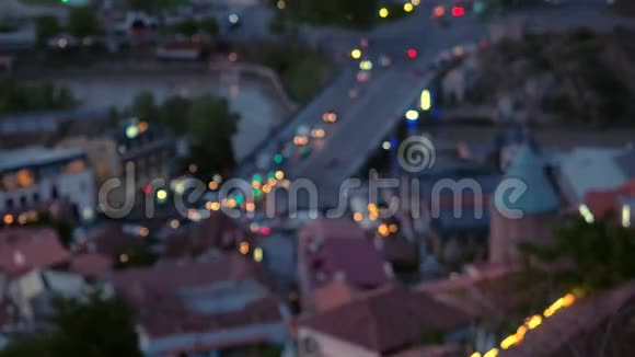 摄像机从上面聚焦到夜晚古老的欧洲城市景色道路上有发光前灯的汽车的运动视频的预览图