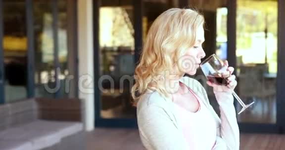 微笑的金发女人站着拿着酒杯视频的预览图