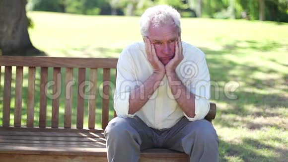 成熟的男人独自坐在长凳上视频的预览图
