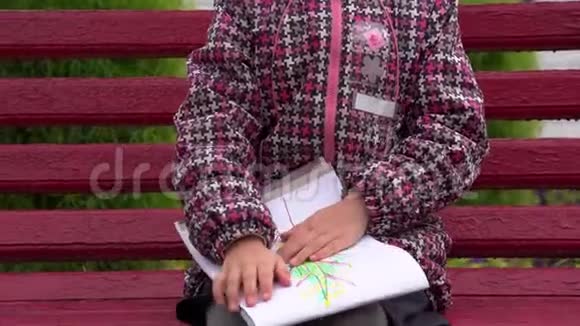 带眼镜的女孩子在他的相册里画了一幅画一个女孩坐在公园的长凳上视频的预览图