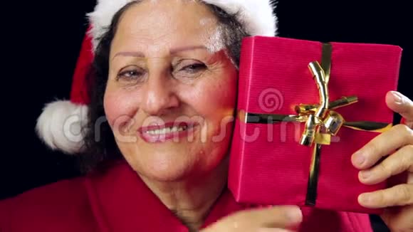 带着圣诞帽的成熟女人带着红色礼物视频的预览图
