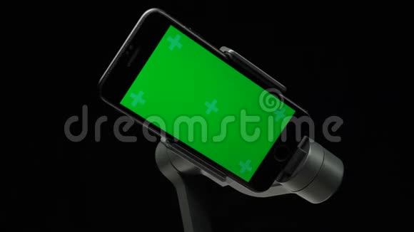 智能手机上带有绿色屏幕的步进式万向节稳定器正在旋转视频的预览图