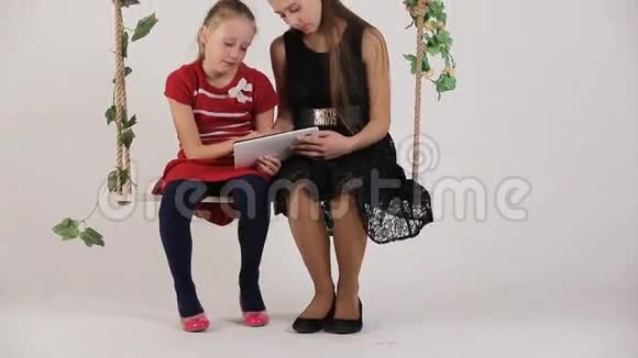 女孩坐在秋千上拿着数码平板电脑视频的预览图