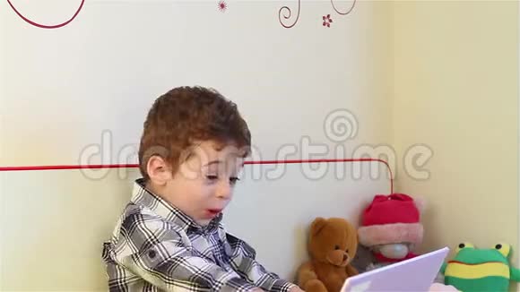 惊讶的小男孩看着笔记本电脑视频的预览图