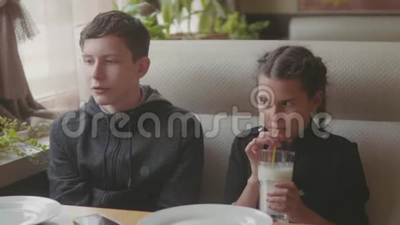 两个可爱的孩子一起喝奶昔或调味饮料室内慢动作视频咖啡馆快餐生活方式男孩视频的预览图