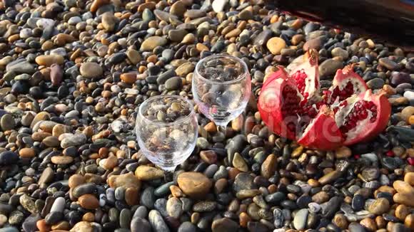 成熟的石榴果和沙滩上的一瓶视频的预览图