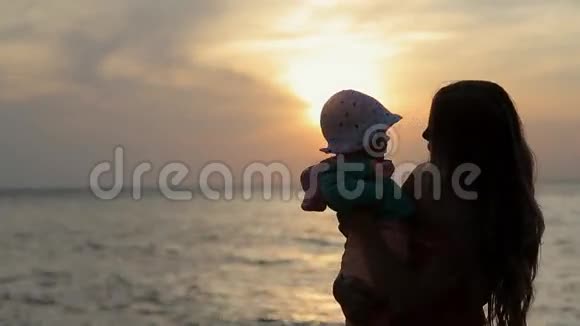 母亲在日落时亲吻婴儿的剪影视频的预览图