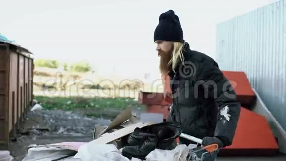 在寒冷的秋日一个留着胡子的流浪汉拿着鞋卡在街上散步视频的预览图