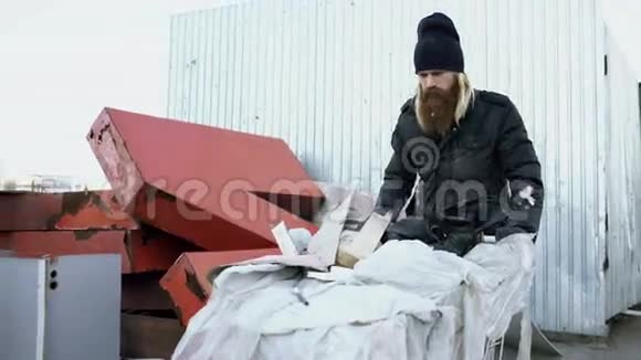 在寒冷的秋日一个留着胡子的流浪汉拿着鞋卡在街上散步视频的预览图