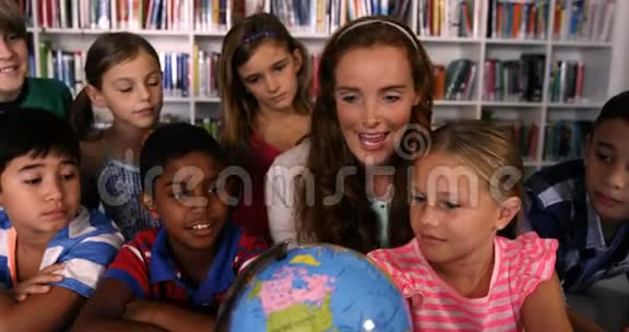 教师协助学童在图书馆阅读地球仪视频的预览图