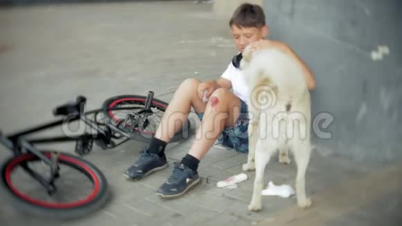 这个男孩从自行车上摔下来后坐在公园里减轻了膝盖的疼痛代表着一辆危险的自行车骑着视频的预览图