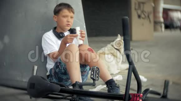 这个男孩从自行车上摔下来后坐在公园里减轻了膝盖的疼痛代表着一辆危险的自行车骑着视频的预览图