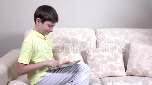 一个拿着平板电脑坐在家里沙发上的小男孩视频的预览图