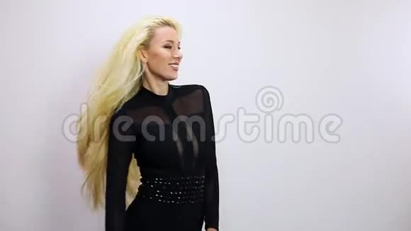 漂亮的金发女人穿着黑色连衣裙在演播室背景下摆姿势慢动作录像视频的预览图