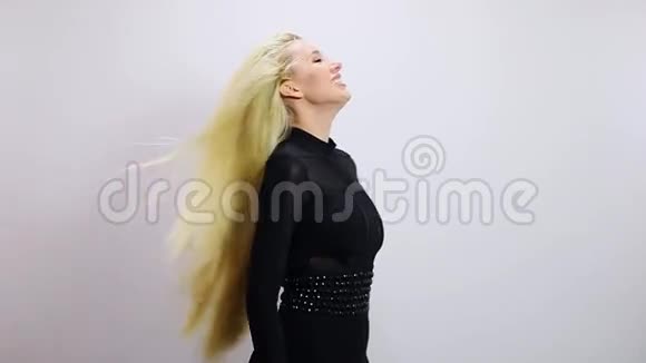 漂亮的金发女人穿着黑色连衣裙在演播室背景下摆姿势慢动作录像视频的预览图