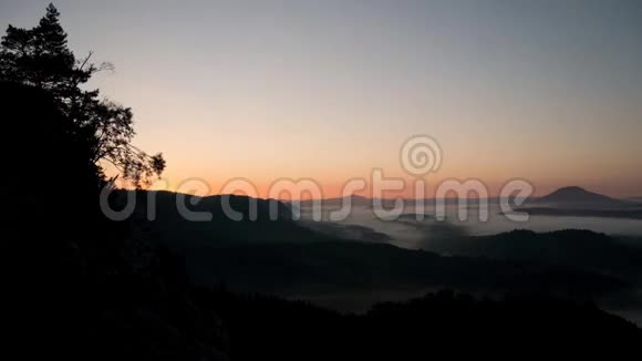 丘陵地带秋日初晴的阳光山峰从橙色和粉红色的雾海增加视频的预览图