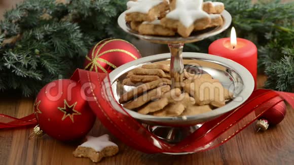 在圣诞节的时候点燃了一支蜡烛前面有一个蛋糕架上面有肉桂饼干丝带圣诞球视频的预览图