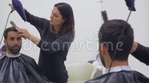 专业美发师在美容院吹风男青年顾客女理发师闭合视频的预览图