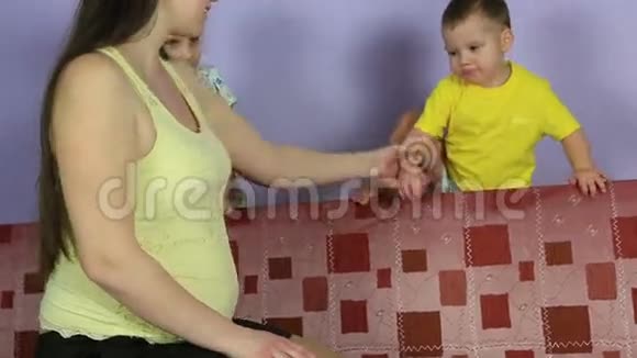 小孩子拥抱和亲吻怀孕母亲的肚子幸福的家庭在等第三个孩子视频的预览图