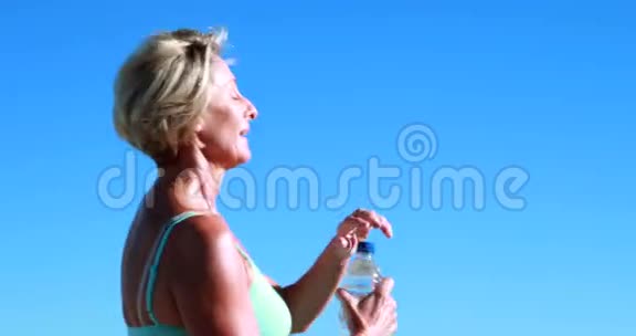 适合的高级女人在跑步时停下来喝一杯视频的预览图