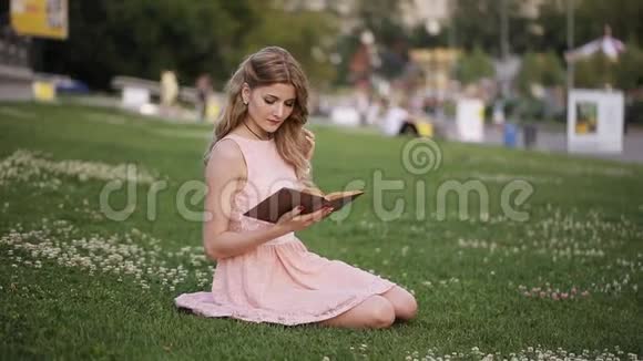 公园里的金发女孩在草地上看书视频的预览图