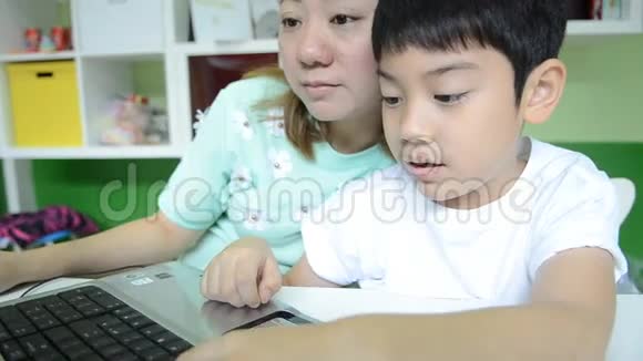 亚洲快乐妈妈在客厅教儿子使用笔记本电脑视频的预览图