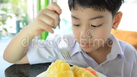 小亚洲可爱的男孩吃一块成熟的菠萝视频的预览图