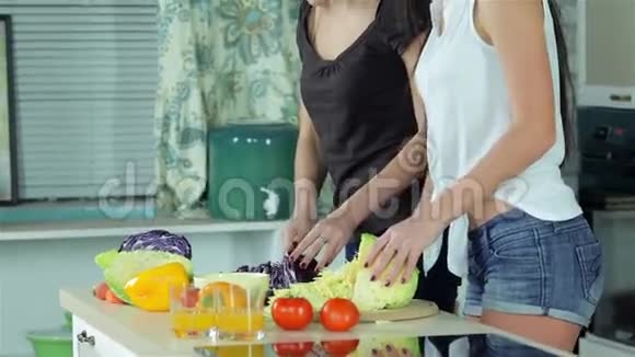 两个微笑的女朋友笑着切蔬菜视频的预览图