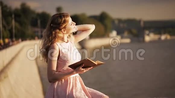 海滨美丽的女孩手里拿着一本书视频的预览图