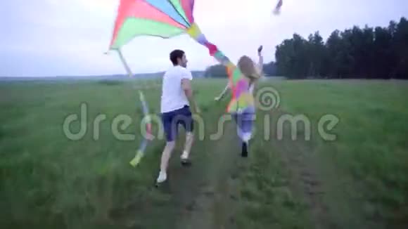 年轻夫妇带着风筝在田野上奔跑视频的预览图