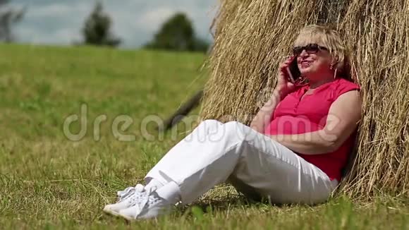 女人坐在干草堆附近通过手机交流视频的预览图