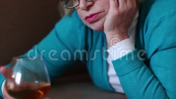 沮丧的女人躺在沙发上喝着白兰地视频的预览图