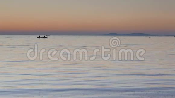 夕阳下平静的海面上有一艘剪影的划艇视频的预览图