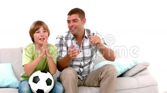 慢动作快乐的父亲和儿子一起看足球电视视频的预览图